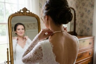 Jeune mariée en robe blanche ajustant un collier de perles
